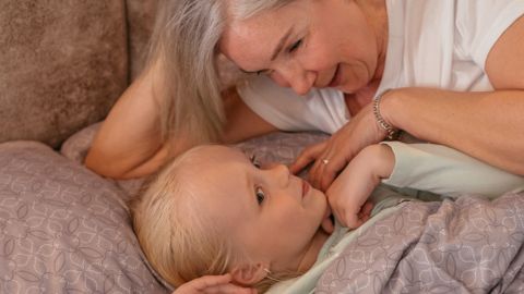 A grandmother and her granddaughter share a loving moment in a cozy bedroom setting.