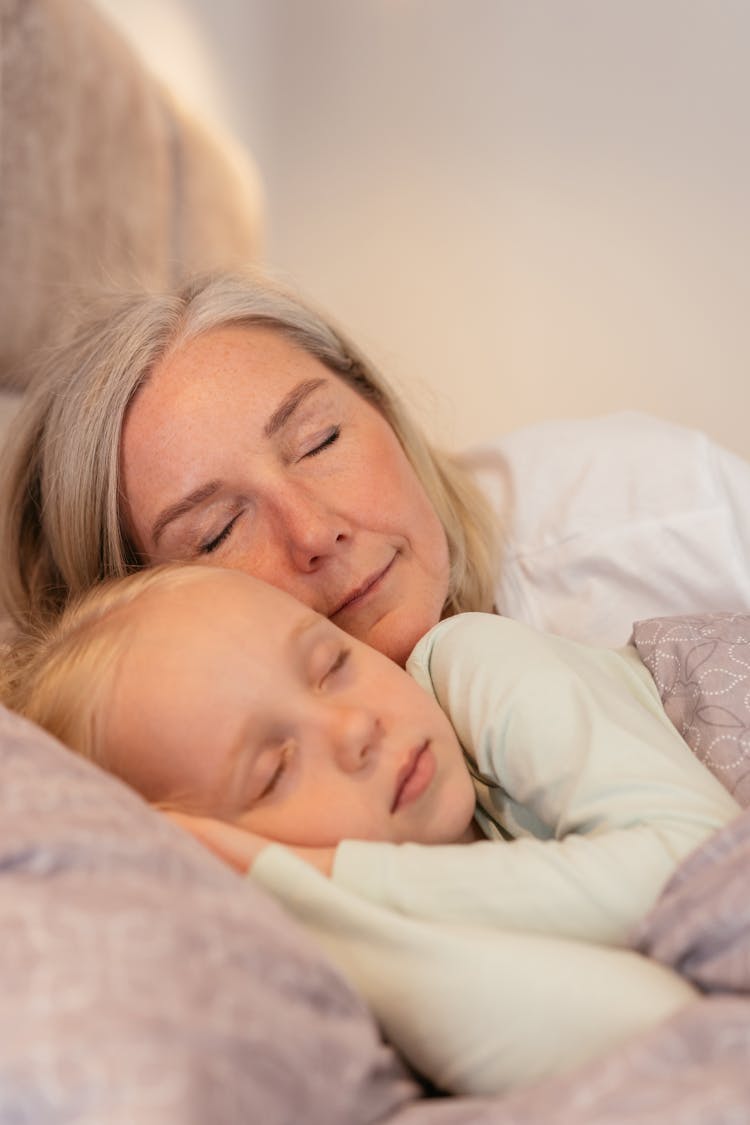 Elderly Woman Sleeping On Bed With A Girl