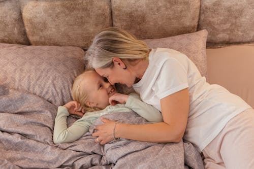 Free Woman in White Shirt Lying on Bed with a Girl Stock Photo