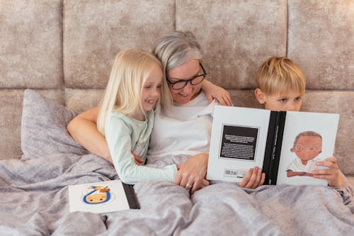 Free Woman with her Grandchildren Reading a Book Stock Photo
