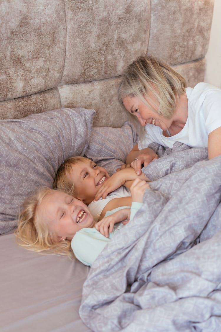 Woman Playing With The Kids On The Bed