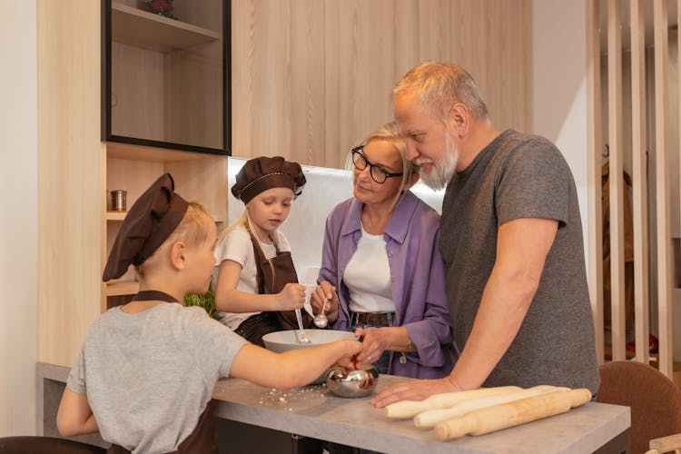 An Elderly Couple Preparing In The Kitchen With Their Grandchildren