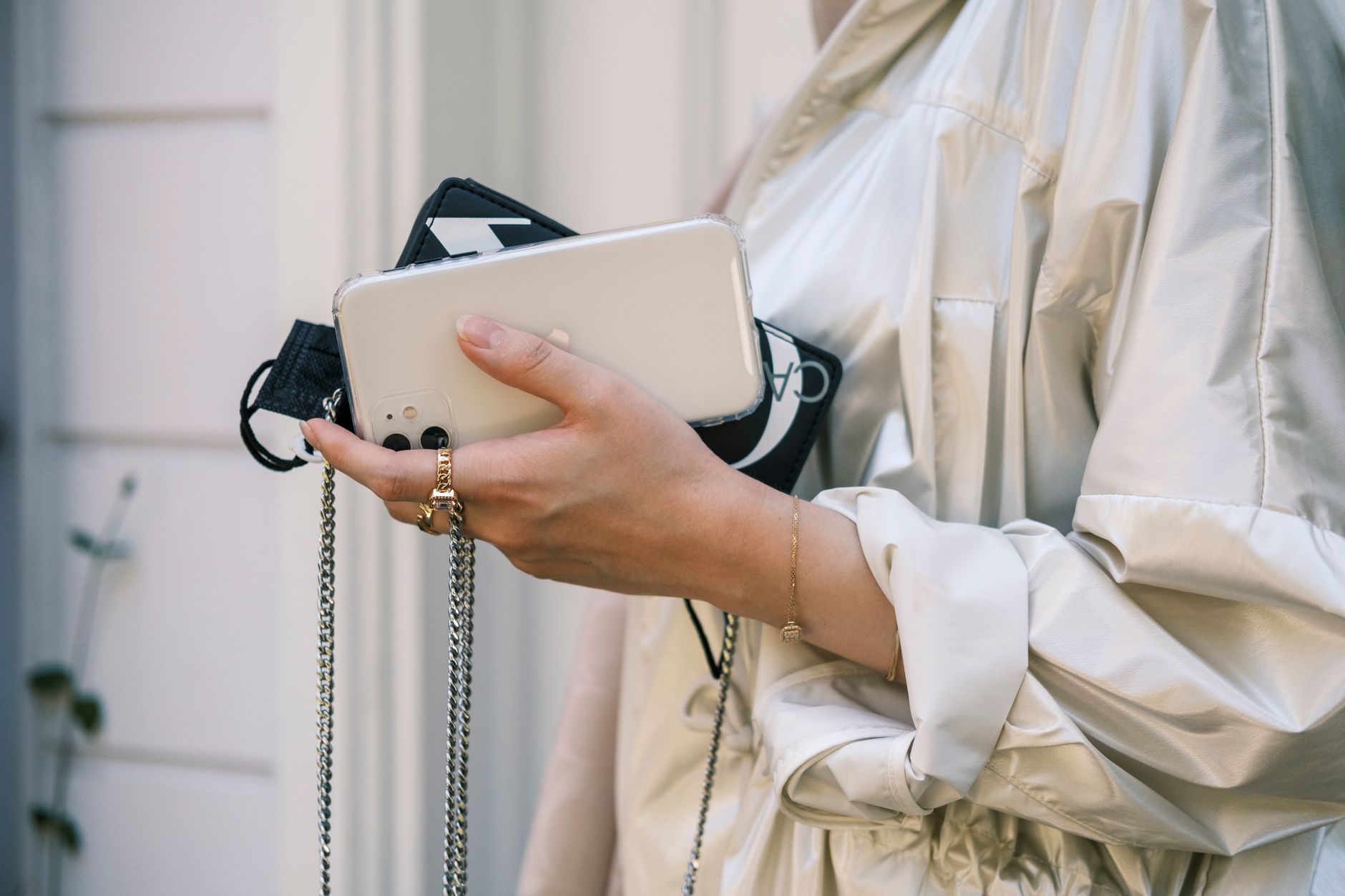 Fashionable woman holding a smartphone with elegant accessories and stylish attire.