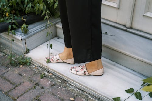 Person in Black Pants and White and Red Floral Flats