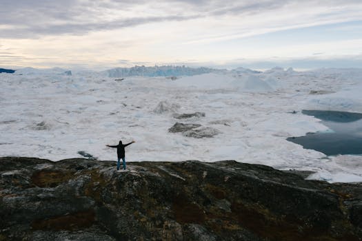 A lone figure with arms spread stands facing a vast frozen landscape, capturing a sense of adventure and solitude