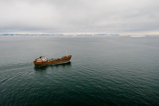 An aerial view of a rustic ship sailing on expansive, calm ocean waters.