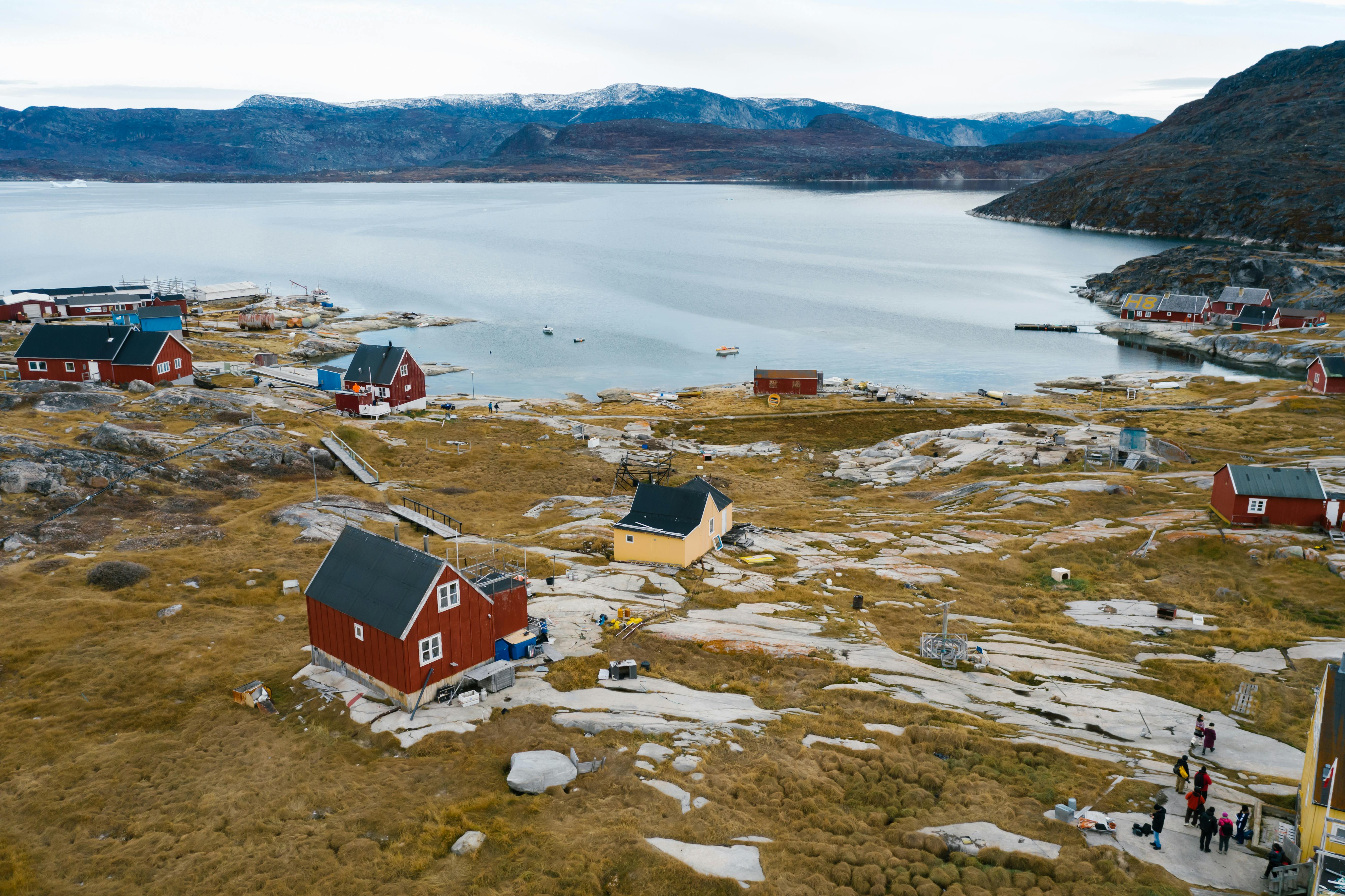 A stunning aerial shot of a colorful coastal village by a serene fjord with mountains.