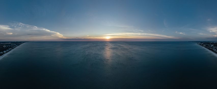 A breathtaking panoramic aerial view of the ocean at sunset with serene skies and tranquil waters.