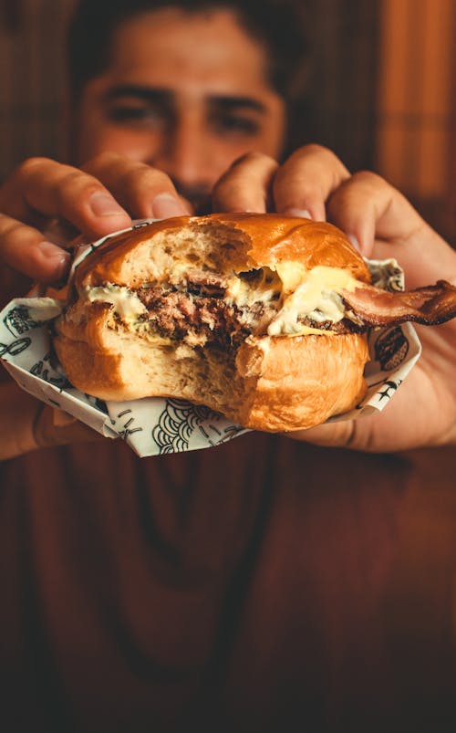 A Person Holding a Burger With Patty