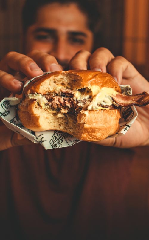 Free Delicious cheeseburger held by hands, showcasing a tantalizing bite. Stock Photo