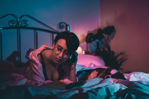 Free A Woman Lying on the Bed while Wearing Eyeglasses Stock Photo