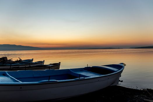 Serene sunset view with boats on a calm coastal shoreline, perfect for relaxation imagery.