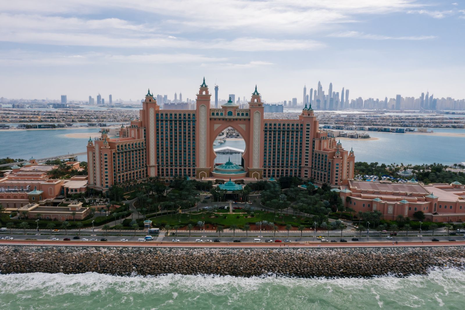 Frontal aerial of Atlantis The Palm behind the rocky crescent breakwater of Palm Jumeirah, with the Dubai Marina skyline on the horizon