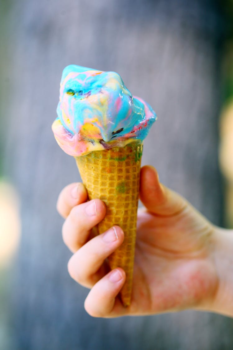 A Person Holding A Cone With Colorful Ice Cream