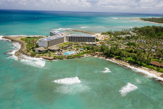 A captivating aerial shot of a beachfront resort surrounded by turquoise waters and lush greenery.