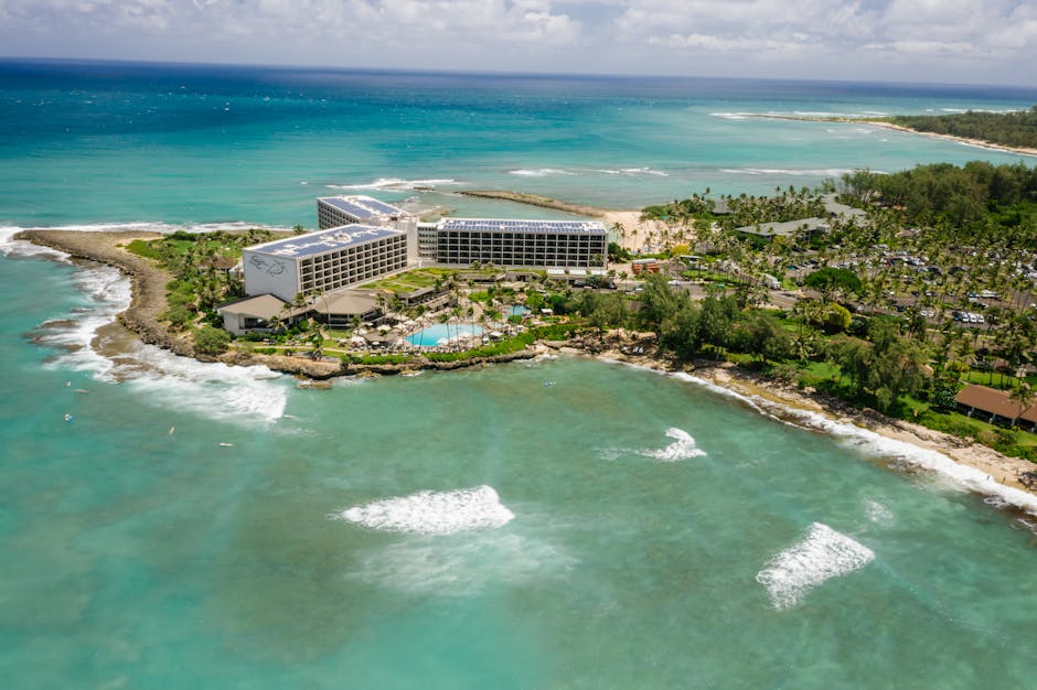Photo by Mikhail Nilov A captivating aerial shot of a beachfront resort surrounded by turquoise waters and lush greenery.