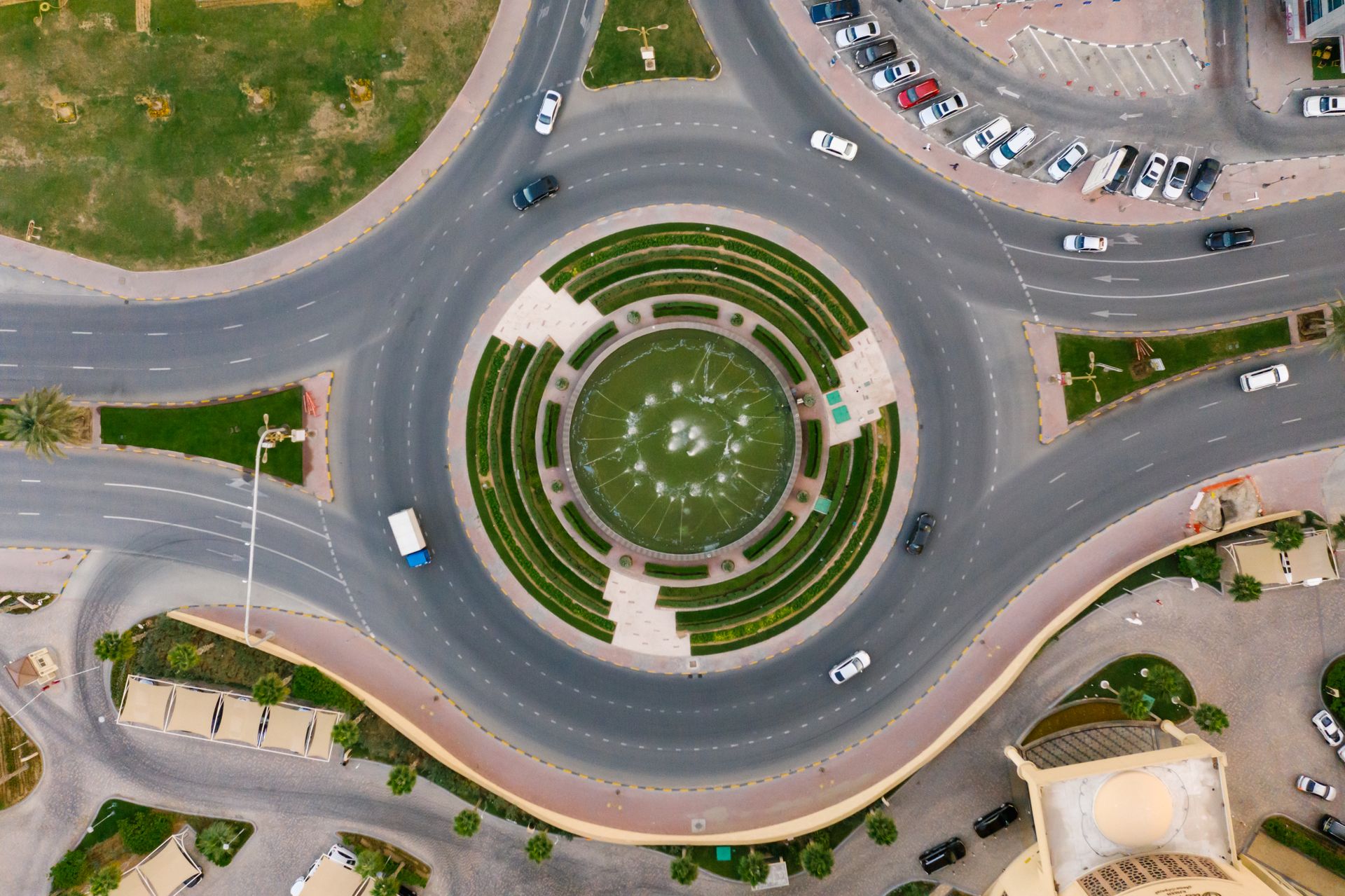 Aerial photo of a circular urban roundabout with cars, greenery, and traffic flow.