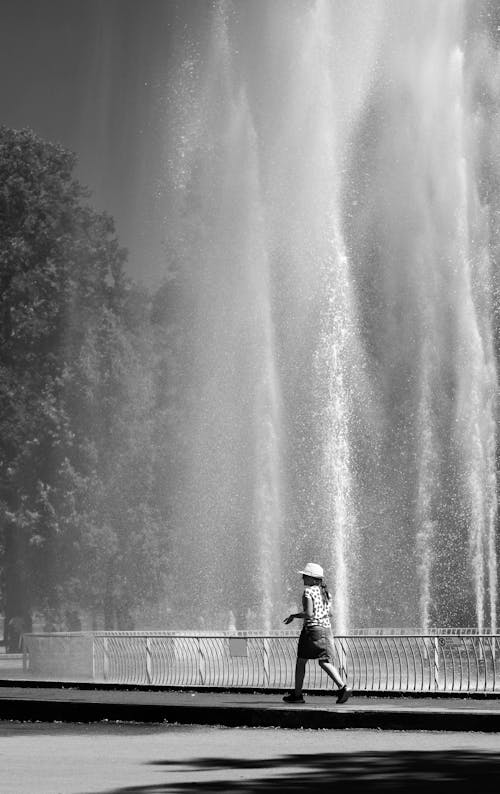 Woman Walking Near a Fountain