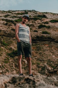 A man in casual attire stands confidently on rugged rocks outdoors.