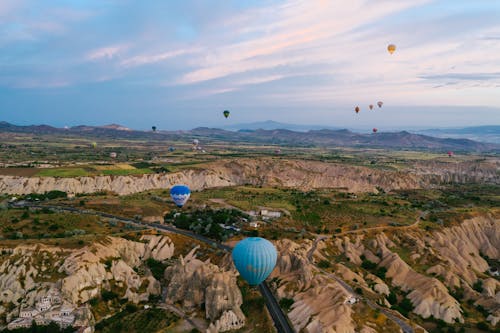 Hot air balloons flying over mountainous terrain