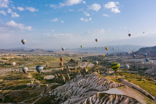 Free Colorful hot air balloons flying over Cappadocia's unique rock formations and landscape. Stock Photo