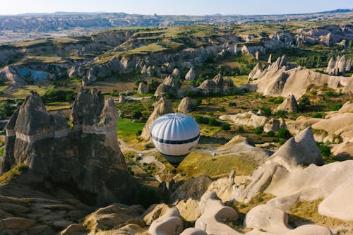 White and Black Hot Air Balloon on Rocky Ground