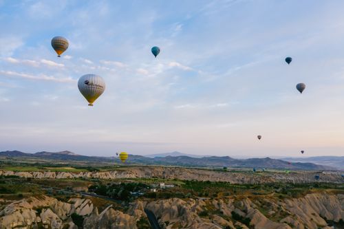 Free Scenic aerial view of hot air balloons floating over the unique landscape of Cappadocia at sunrise. Stock Photo