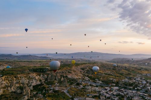 Free Stunning view of hot air balloons floating over Cappadocia's unique landscape during sunrise. Stock Photo