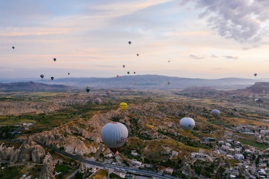 Stunning aerial view of hot air balloons floating over Cappadocia at sunrise, showcasing picturesque landscapes.