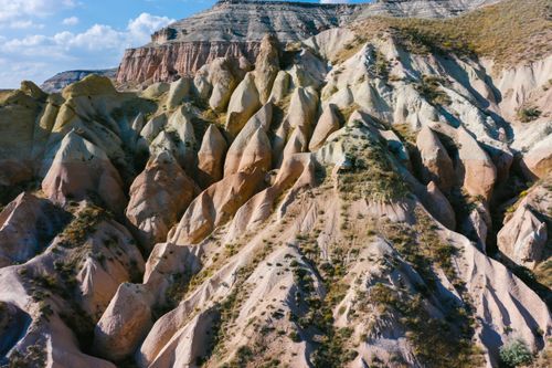 Free A breathtaking aerial shot capturing the sunlit, eroded rock formations in a rural landscape. Stock Photo