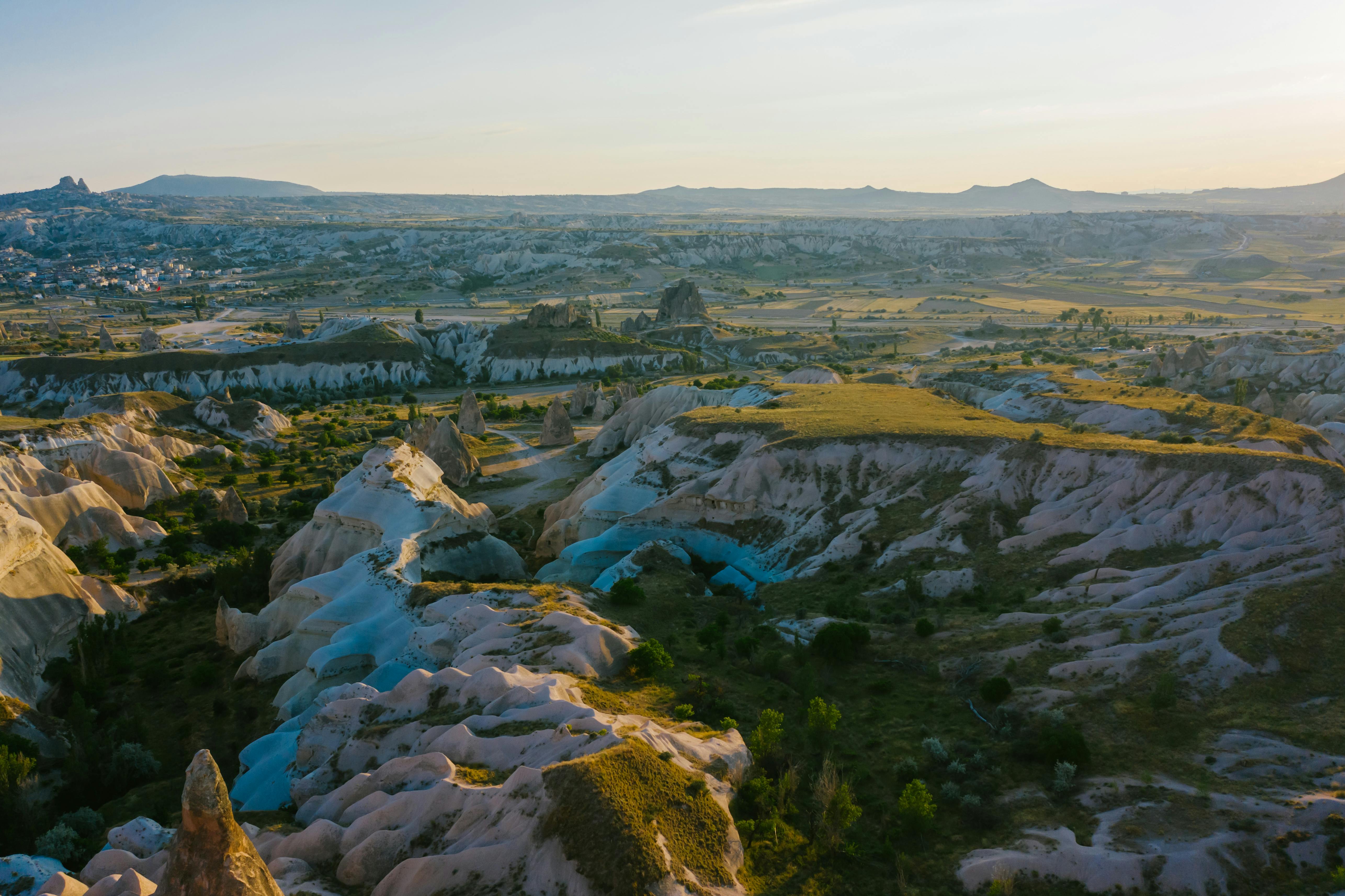 A panoramic aerial view of the unique rock formations and valleys in Cappadocia at sunset.