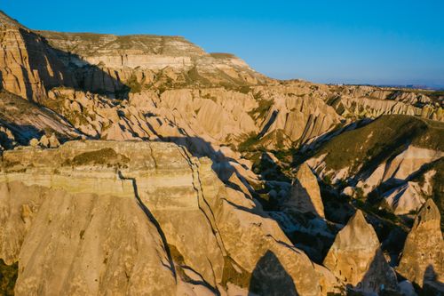 Free Aerial view of the rocky formations and valleys of Cappadocia under clear blue skies. Stock Photo