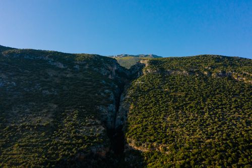 Free Capture of a serene mountainous landscape with rich greenery under a clear blue sky. Stock Photo