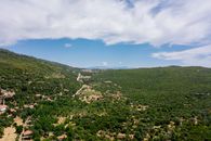 A scenic aerial view of a lush green valley with rolling hills under a clear blue sky, perfect for travel exploration.