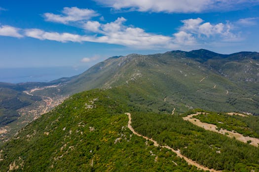 Stunning aerial view of a lush green mountainous landscape under a blue sky.