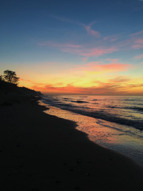 Waves Crashing on Seashore During Sunset