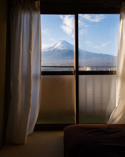 Free A picturesque view of Mount Fuji through a window with curtains in a serene setting. Stock Photo