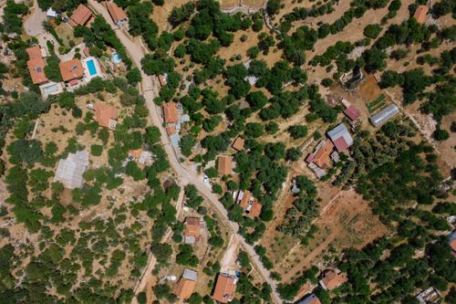 Free Aerial shot of rural houses and roads amidst lush green landscapes, showcasing a serene countryside setting. Stock Photo