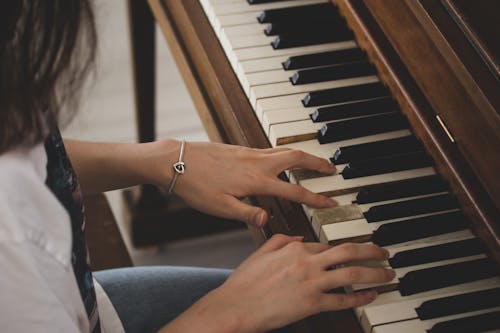 A Person in Silver Bracelet Playing Piano