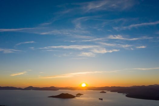 A stunning sunset over a calm ocean with silhouetted islands and vibrant skies.