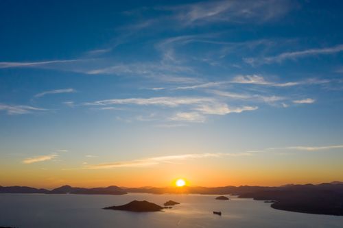 Free A stunning sunset over a calm ocean with silhouetted islands and vibrant skies. Stock Photo