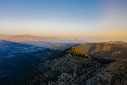 Free A stunning aerial view of mountains at sunset casting long shadows across a vast landscape. Stock Photo