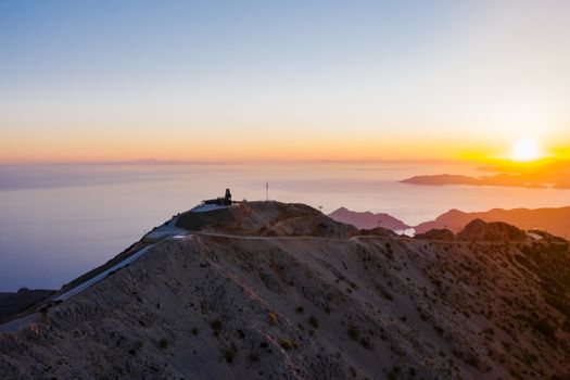 Breathtaking aerial view of mountains at sunset with a vibrant horizon. A serene and majestic nature scene.