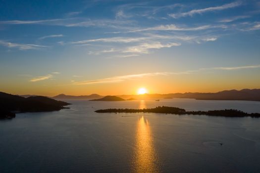 A breathtaking sunset view over a tranquil sea with distant islands and a vibrant sky.
