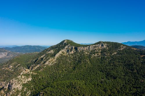 Free Aerial view of lush forested mountain range under clear blue sky. Stock Photo