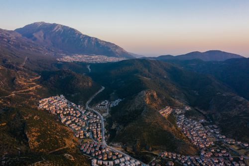 Free Discover an aerial view of a town nestled in mountains at sunset, showcasing scenic beauty and urban charm. Stock Photo