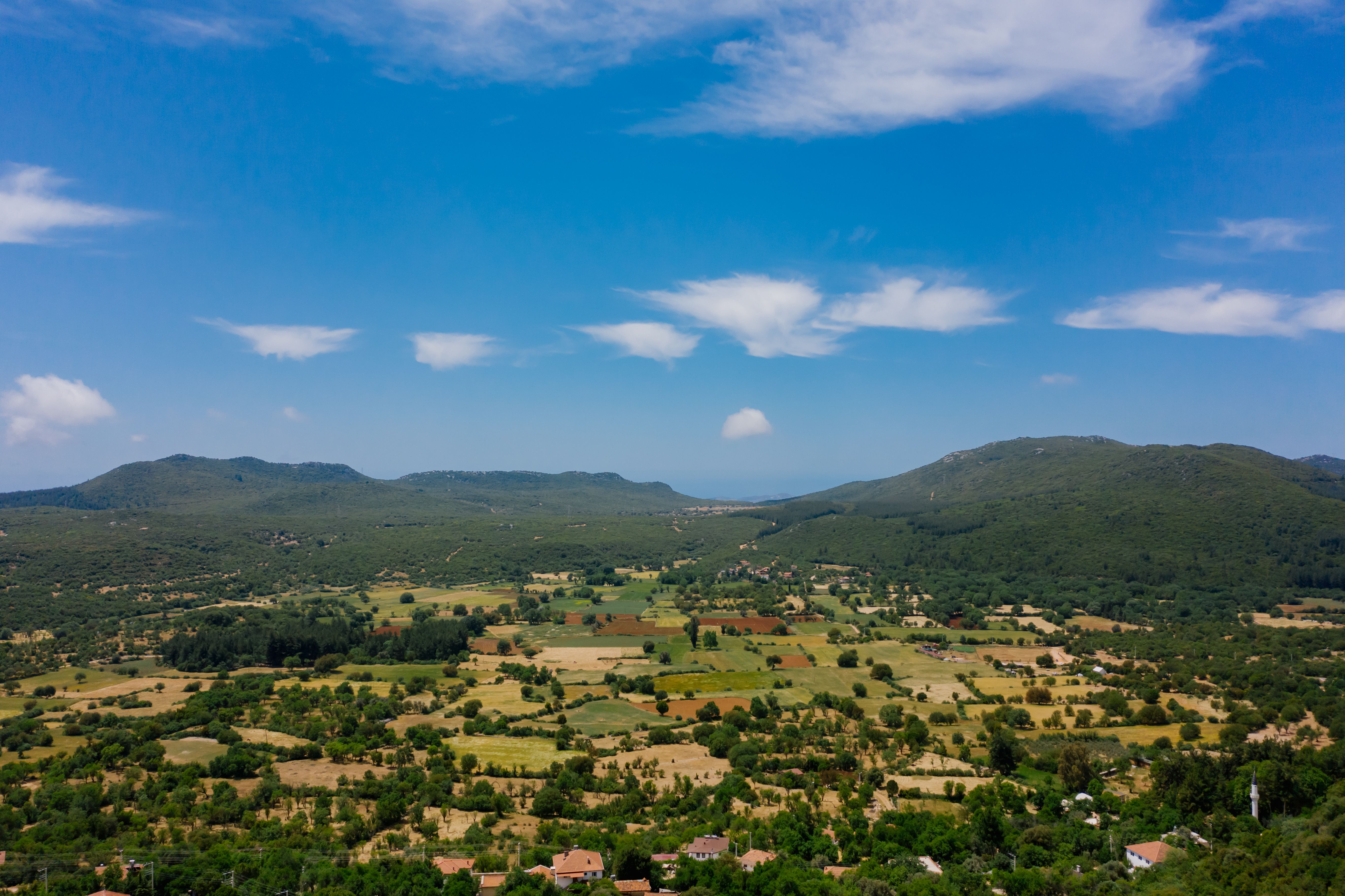 Aerial View of Green Field and Mountains Under Blue Sky · Free Stock Photo