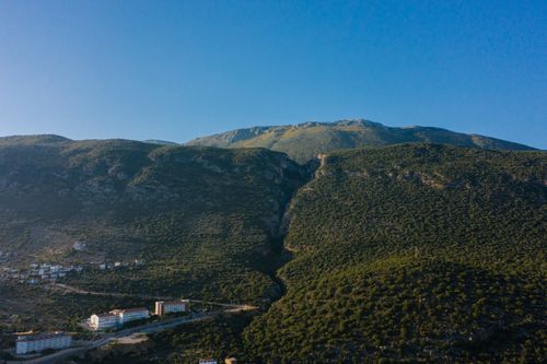 Free Stunning aerial view of a peaceful town nestled in lush green hills with clear blue skies. Stock Photo