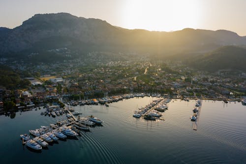 Aerial View of Boats in the Harbor and Sun Setting behind the Mountains 