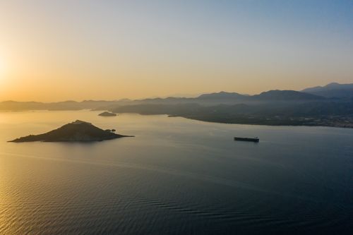 Free Stunning aerial view of an island and sea at sunset with a ship in the distance. Stock Photo